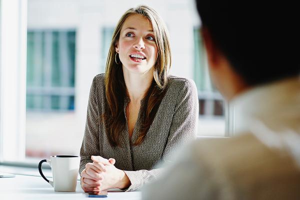 Smiling woman talking to man in an office setting.